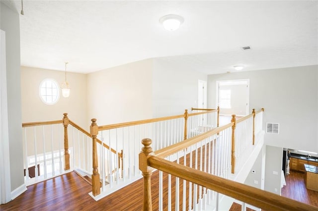 hall featuring visible vents, a notable chandelier, wood finished floors, and an upstairs landing