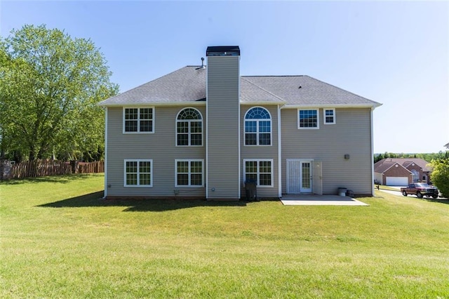 back of house featuring a yard, a patio area, a chimney, and fence