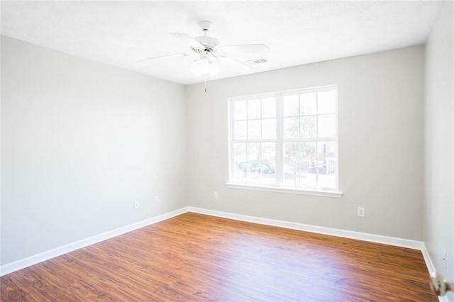 unfurnished room featuring wood finished floors, visible vents, baseboards, and ceiling fan