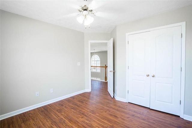 unfurnished bedroom with wood finished floors, a closet, a ceiling fan, and baseboards