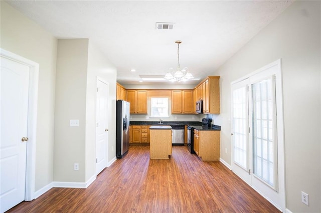 kitchen featuring dark wood-style floors, stainless steel appliances, dark countertops, visible vents, and a notable chandelier