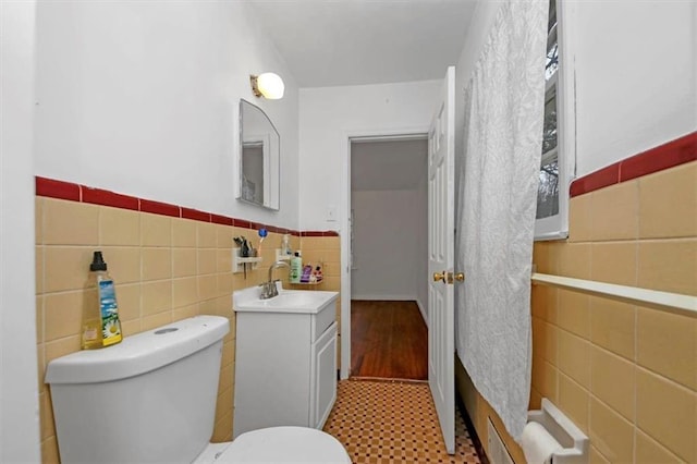 bathroom with vanity, tile walls, and toilet