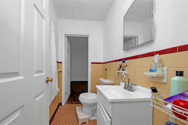 bathroom featuring vanity, tile walls, and toilet