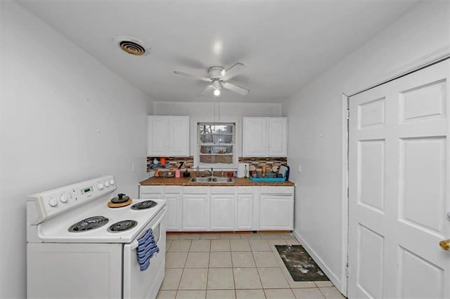 kitchen with electric stove, sink, light tile patterned floors, ceiling fan, and white cabinetry