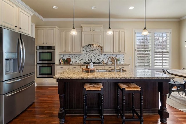 kitchen featuring light stone countertops, appliances with stainless steel finishes, sink, and decorative light fixtures