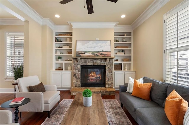 living room featuring ornamental molding, a fireplace, dark hardwood / wood-style flooring, and built in shelves