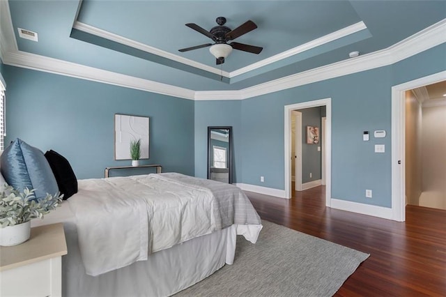 bedroom featuring ceiling fan, ornamental molding, a tray ceiling, and dark hardwood / wood-style flooring