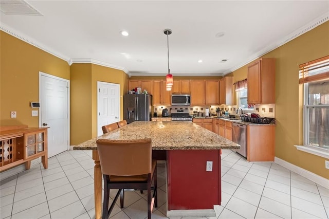 kitchen with a center island, pendant lighting, a breakfast bar area, appliances with stainless steel finishes, and ornamental molding