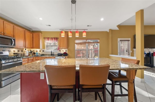 kitchen featuring pendant lighting, a kitchen island, light tile patterned floors, and stainless steel appliances