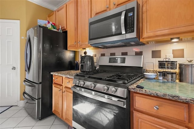 kitchen with backsplash, light tile patterned flooring, stone countertops, and appliances with stainless steel finishes