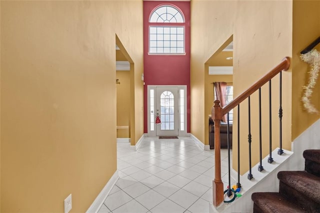 entrance foyer featuring a high ceiling, light tile patterned floors, and ornamental molding