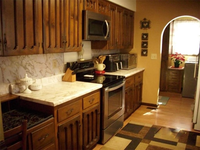 kitchen with stainless steel appliances, tasteful backsplash, and light hardwood / wood-style flooring