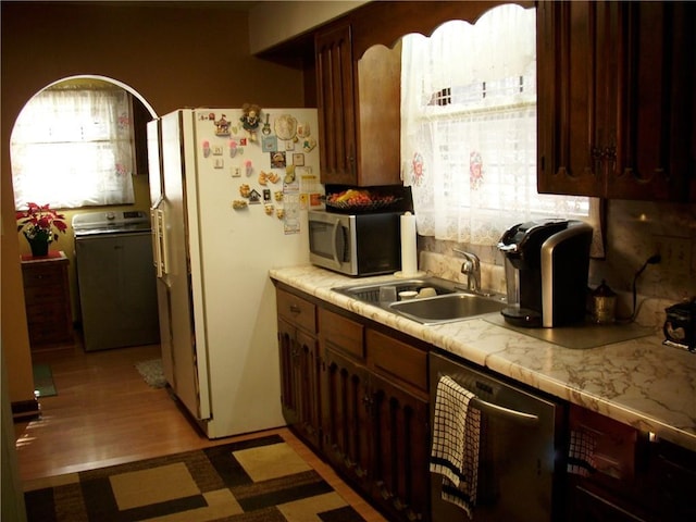 kitchen featuring light hardwood / wood-style floors, stainless steel appliances, washer / dryer, and sink