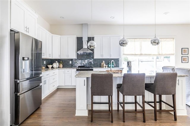 kitchen with pendant lighting, a breakfast bar area, white cabinets, a kitchen island with sink, and stainless steel appliances