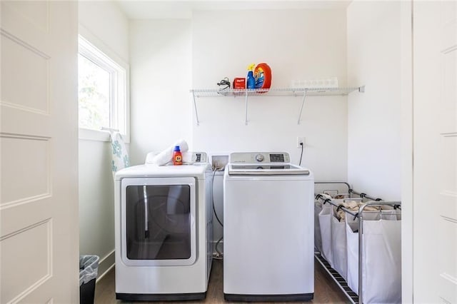 clothes washing area with washing machine and dryer and dark hardwood / wood-style flooring