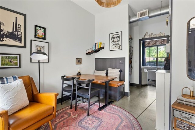 dining room with baseboards, concrete flooring, a towering ceiling, and visible vents