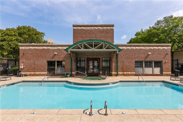 community pool with a patio, a hot tub, fence, and french doors