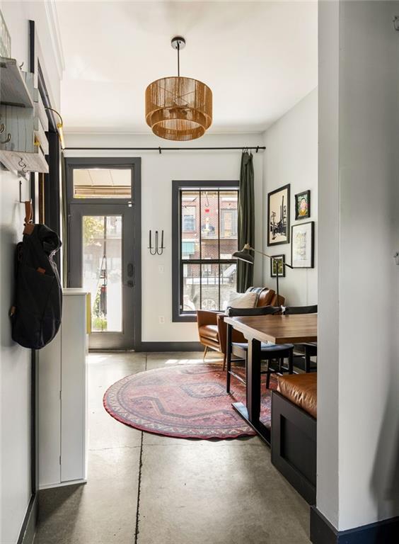 foyer with baseboards, a wealth of natural light, and finished concrete flooring