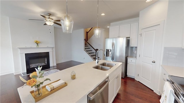 kitchen featuring stainless steel appliances, dark hardwood / wood-style flooring, sink, ceiling fan, and tasteful backsplash