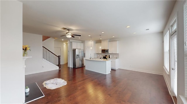 interior space with stainless steel appliances, an island with sink, ceiling fan, dark hardwood / wood-style floors, and white cabinets