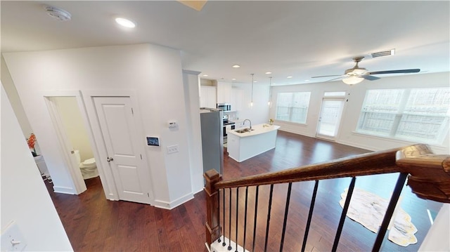 interior space with baseboards, ceiling fan, wood finished floors, and visible vents