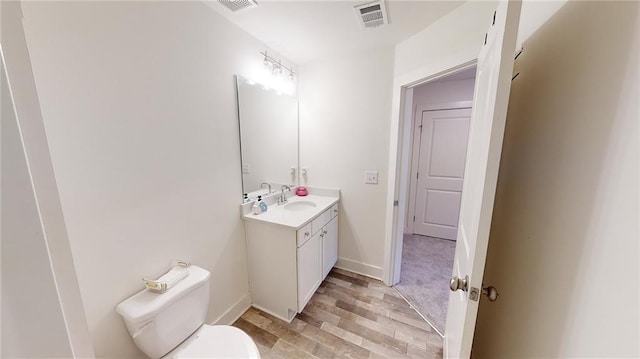 bathroom with visible vents, vanity, wood finished floors, toilet, and baseboards