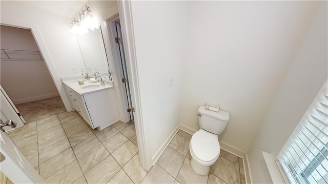 bathroom featuring toilet, baseboards, tile patterned flooring, and vanity