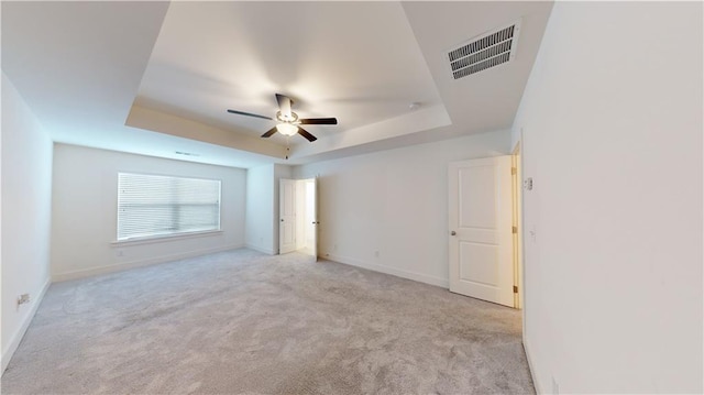 carpeted empty room with a raised ceiling and ceiling fan