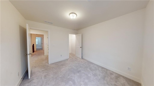 unfurnished bedroom featuring baseboards, visible vents, and light carpet