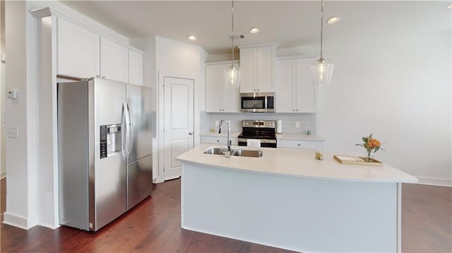 kitchen featuring hanging light fixtures, appliances with stainless steel finishes, sink, dark hardwood / wood-style floors, and an island with sink