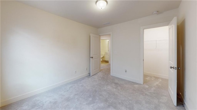 unfurnished bedroom with light carpet, a spacious closet, and a closet