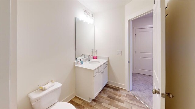 bathroom with toilet, baseboards, wood finished floors, and vanity