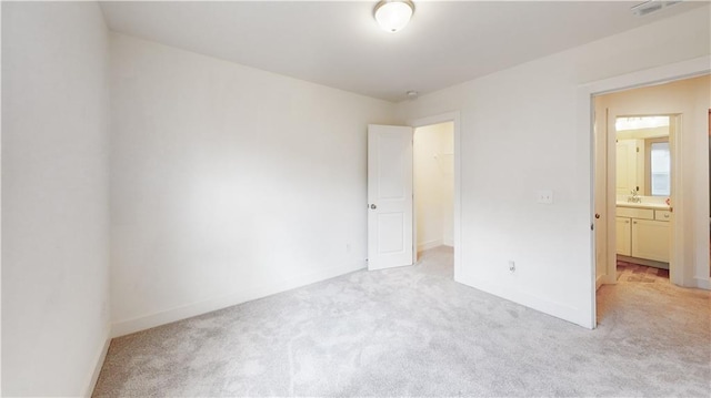 unfurnished bedroom with light colored carpet and connected bathroom