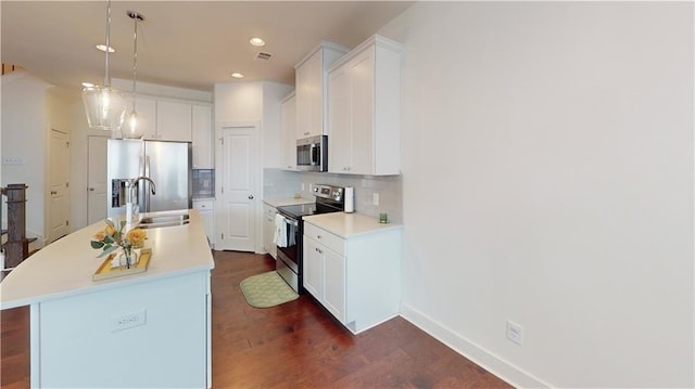 kitchen with a kitchen island with sink, pendant lighting, sink, dark wood-type flooring, and appliances with stainless steel finishes