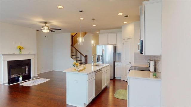 kitchen with stainless steel appliances, dark hardwood / wood-style floors, ceiling fan, pendant lighting, and a kitchen island with sink