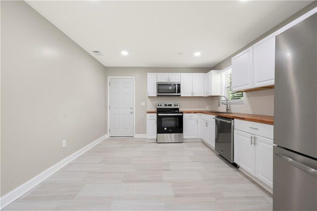 2159 Fairburn Rd SW, Atlanta, GA 30331 - kitchen with appliances with stainless steel finishes, a sink, wooden counters, white cabinets, and recessed lighting