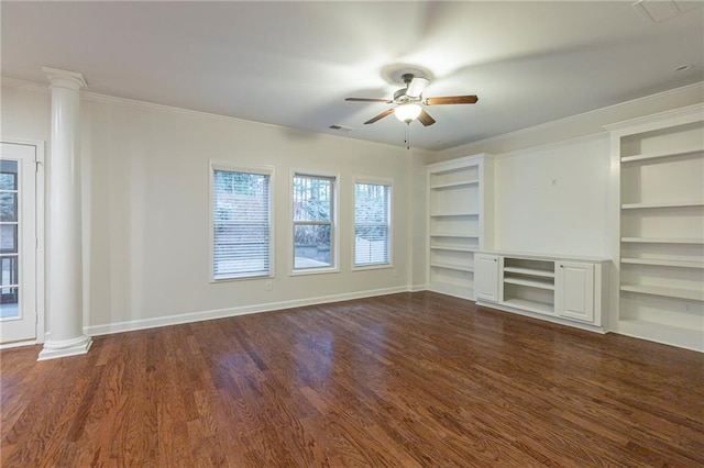 unfurnished living room with ornate columns, ceiling fan, built in shelves, dark wood-type flooring, and crown molding