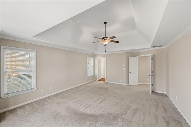 unfurnished room featuring plenty of natural light, ornamental molding, light carpet, and a tray ceiling