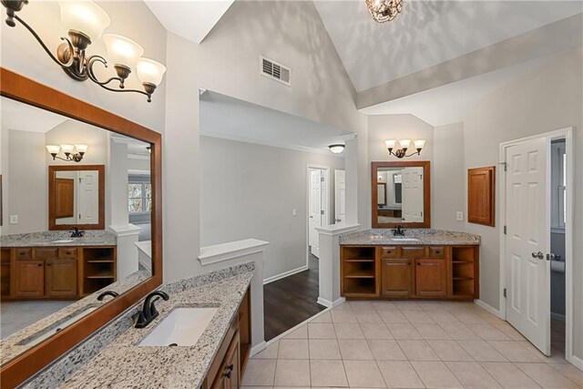 bathroom with tile patterned floors, vanity, high vaulted ceiling, and a notable chandelier