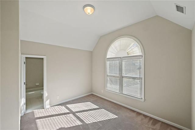 carpeted spare room with vaulted ceiling