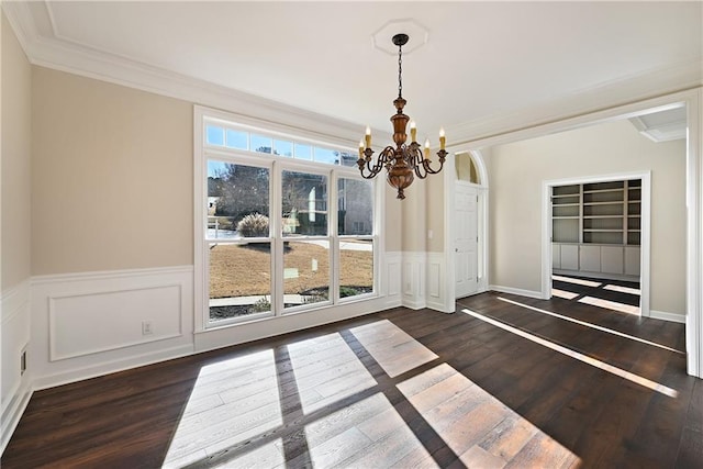 unfurnished dining area featuring ornamental molding, dark wood-type flooring, and an inviting chandelier