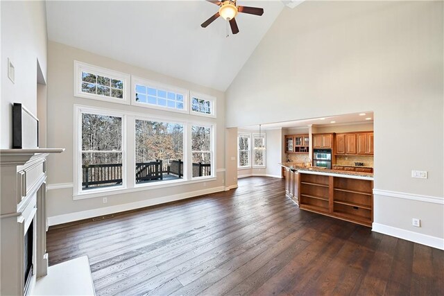 living room with a wealth of natural light, ceiling fan, high vaulted ceiling, and dark hardwood / wood-style floors