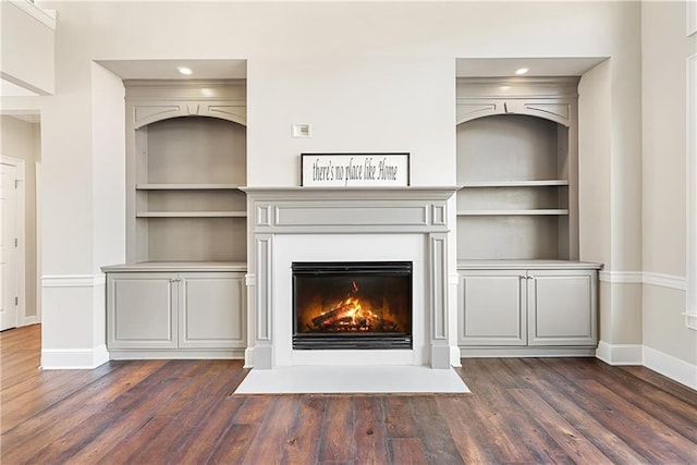 unfurnished living room with built in shelves and dark hardwood / wood-style flooring