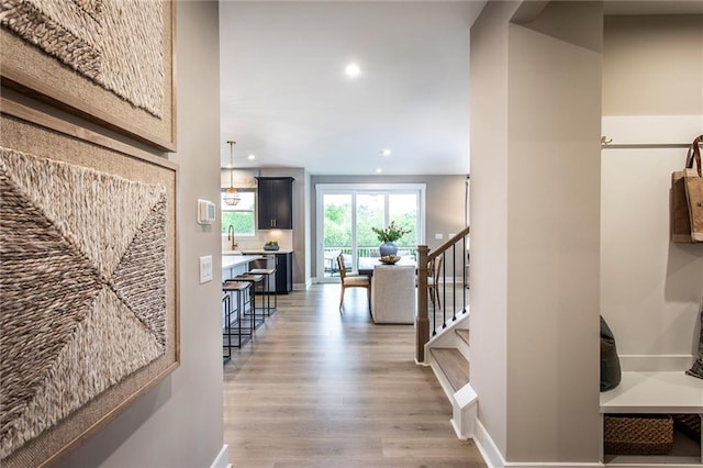 7505 Woolf Way, Cumming, GA 30028 - hall featuring light wood-style flooring, stairs, a sink, recessed lighting, and baseboards