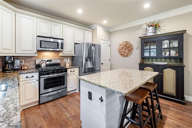 501 Rabun Ct, Canton, GA 30115 - kitchen featuring stainless steel appliances, dark wood finished floors, a kitchen breakfast bar, crown molding, and light stone counters