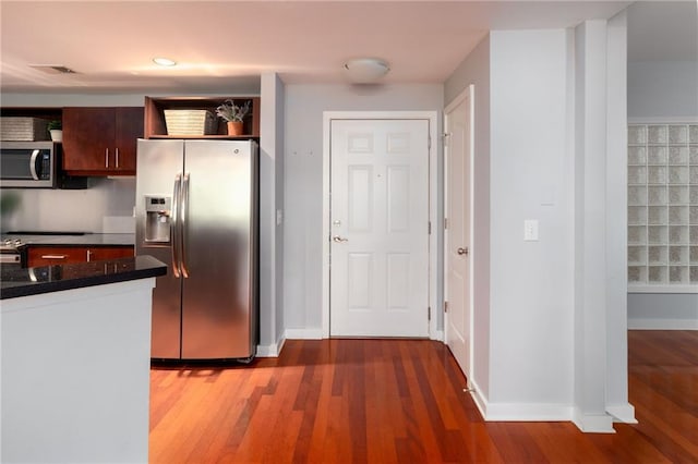 kitchen featuring appliances with stainless steel finishes, dark brown cabinets, and dark wood-type flooring