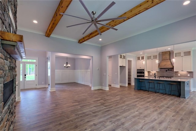 6449 Snelling Mill Rd, Flowery Branch, GA 30542 - unfurnished living room featuring a stone fireplace, beamed ceiling, a chandelier, wood finished floors, and ceiling fan