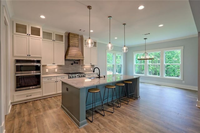 6449 Snelling Mill Rd, Flowery Branch, GA 30542 - kitchen with premium range hood, double oven, a kitchen bar, tasteful backsplash, and a kitchen island with sink