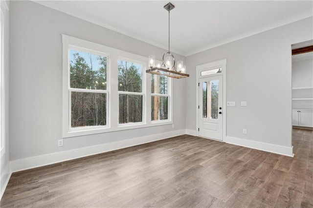 unfurnished dining area featuring an inviting chandelier, crown molding, and dark wood-type flooring