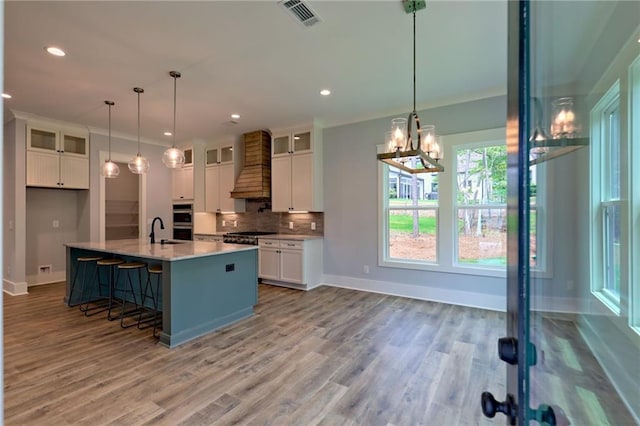 6449 Snelling Mill Rd, Flowery Branch, GA 30542 - kitchen with custom range hood, white cabinetry, a sink, decorative backsplash, and glass insert cabinets